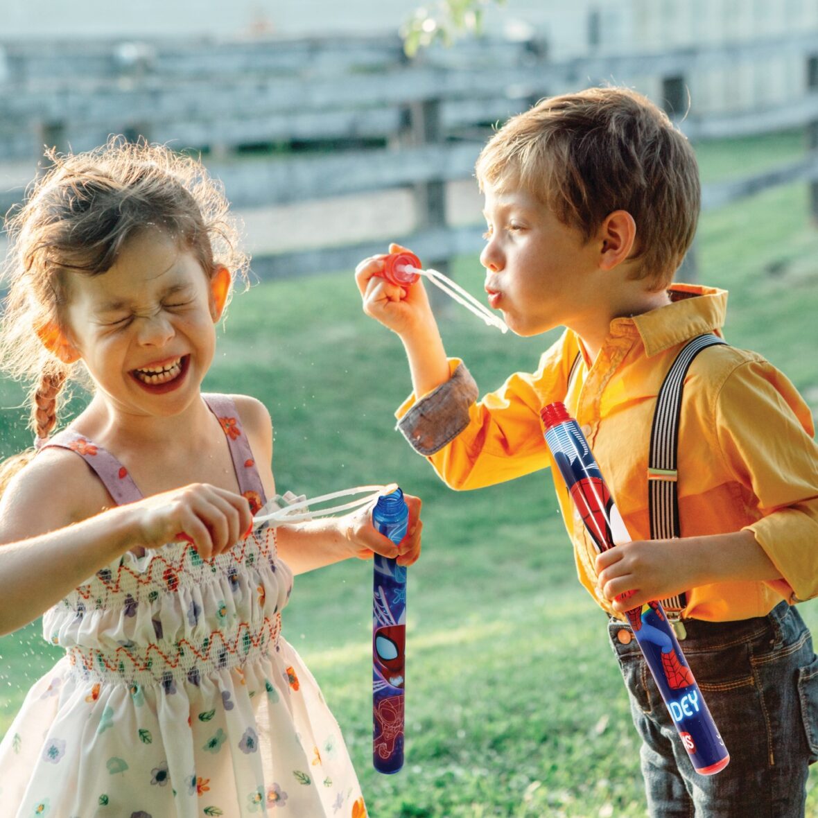 Funny Caucasian children girl and boy blowing soap bubbles in pa
