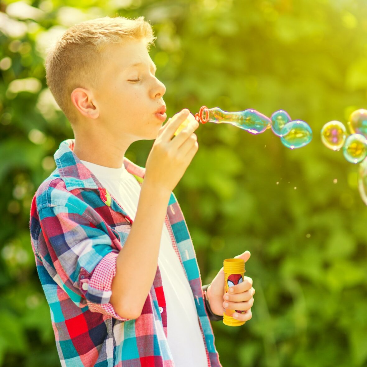 Portrait of a young boy blowing soap bubbles in a park