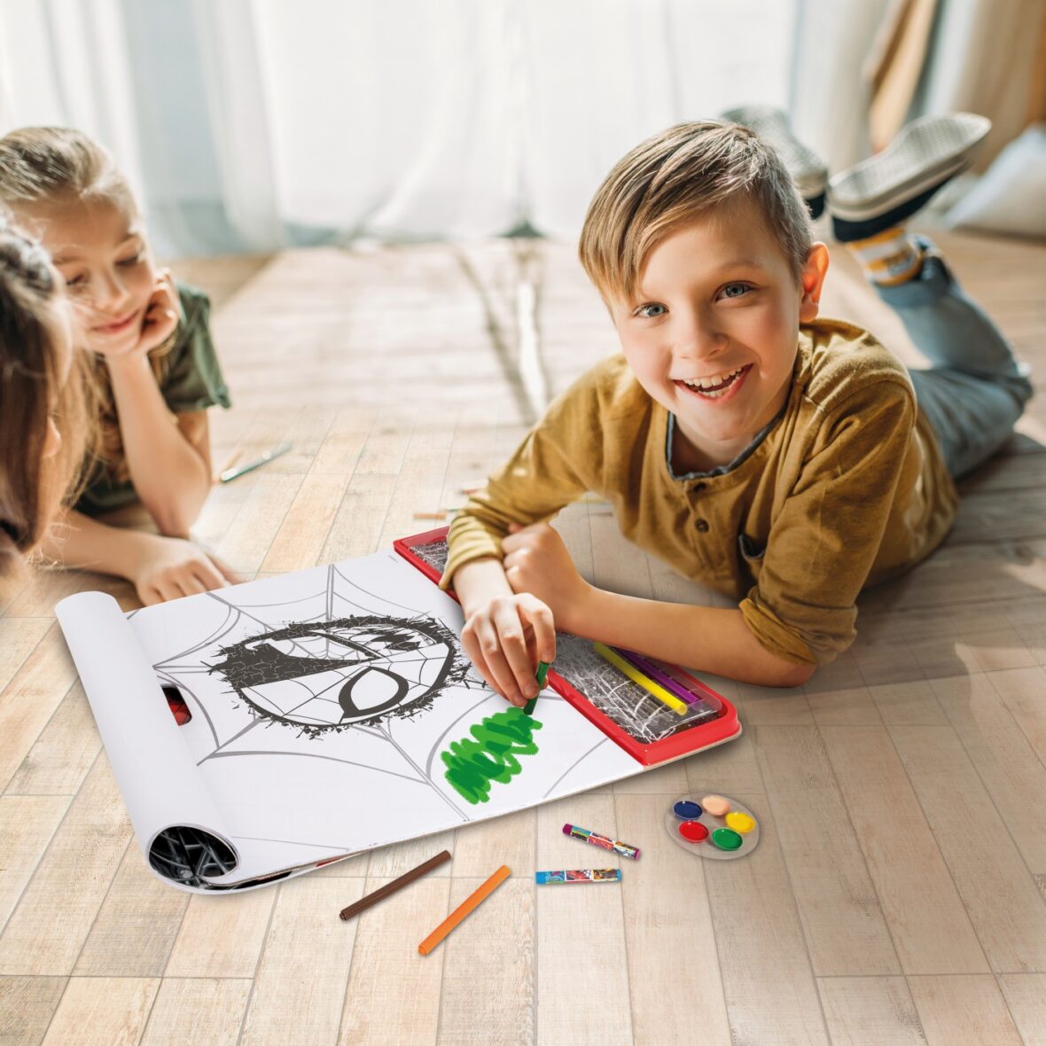 cute kids drawing on paper with pencils while lying on floor